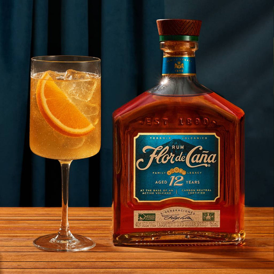 Ron Flor de Caña 12 años junto a un trago con naranja